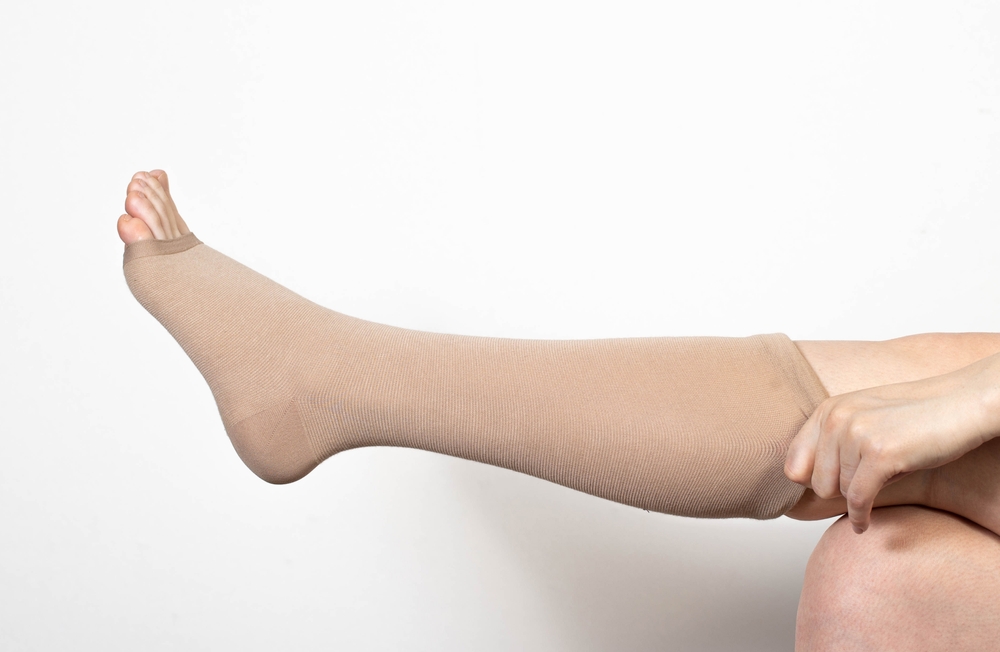 Woman puts on compression socks to help alleviate varicose veins in pregnancy.