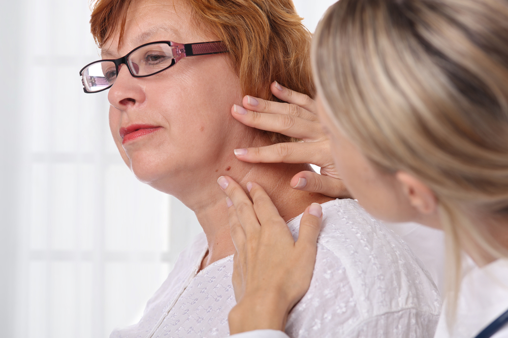 Older woman gets examined by medical professional to have skin tags removed.