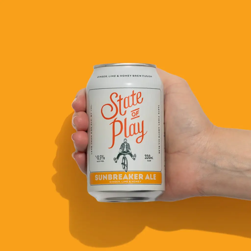Hand holds can of low-alcohol beer on orange background, drinking less alcohol has better treatment options.