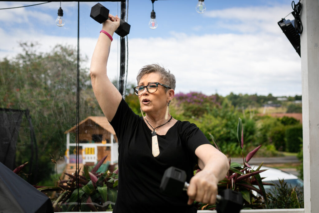 Maori woman does arm exercises outside using small dumbells to get fit for better treatment outcomes.