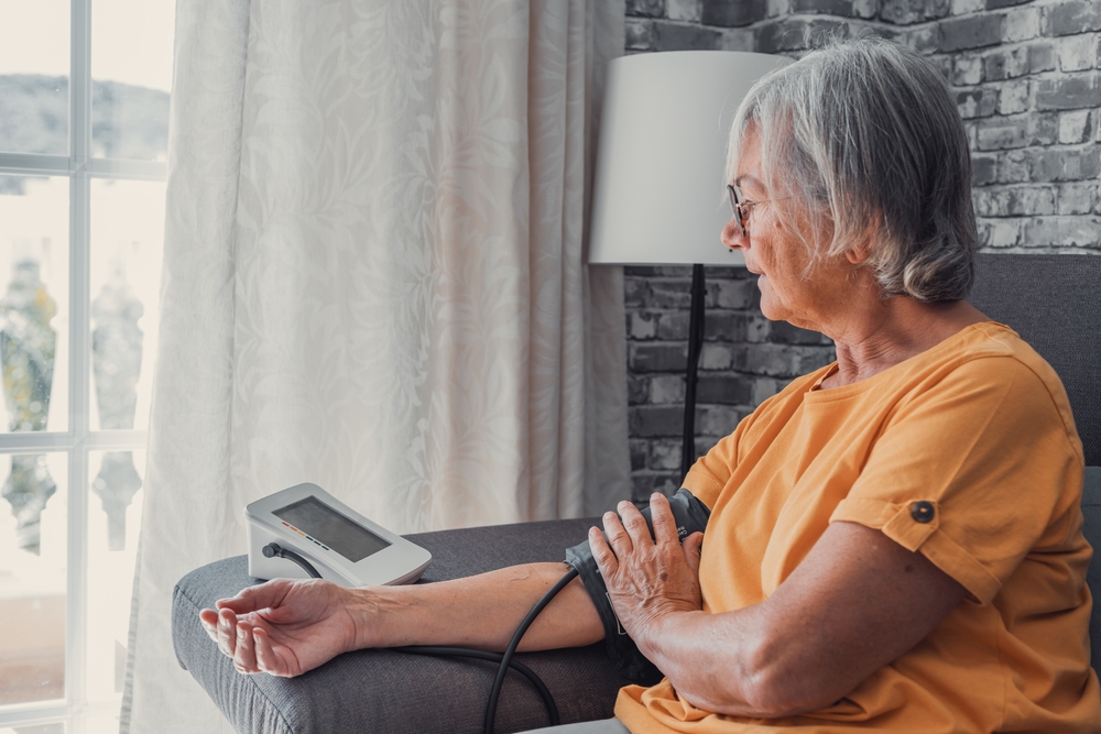 Older woman takes blood pressure at home to monitor high blood pressure for better treatment outcomes.