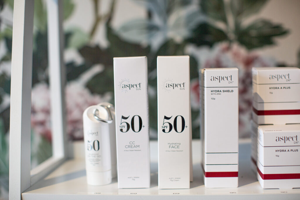 Aspect Sun SPF 50+ products on a shelf with Aspect Dr Hydra Shield and Hydra A Plus products.